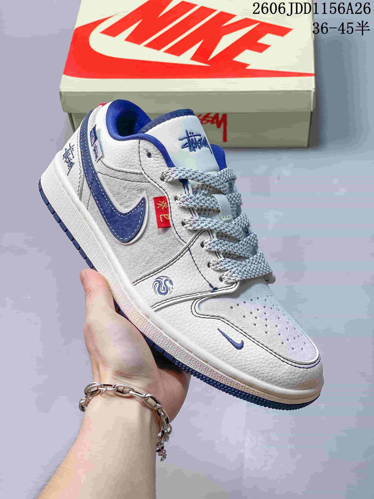 Close view of a white low-top sneaker with blue accents, patterned overlays and a red fabric detail.