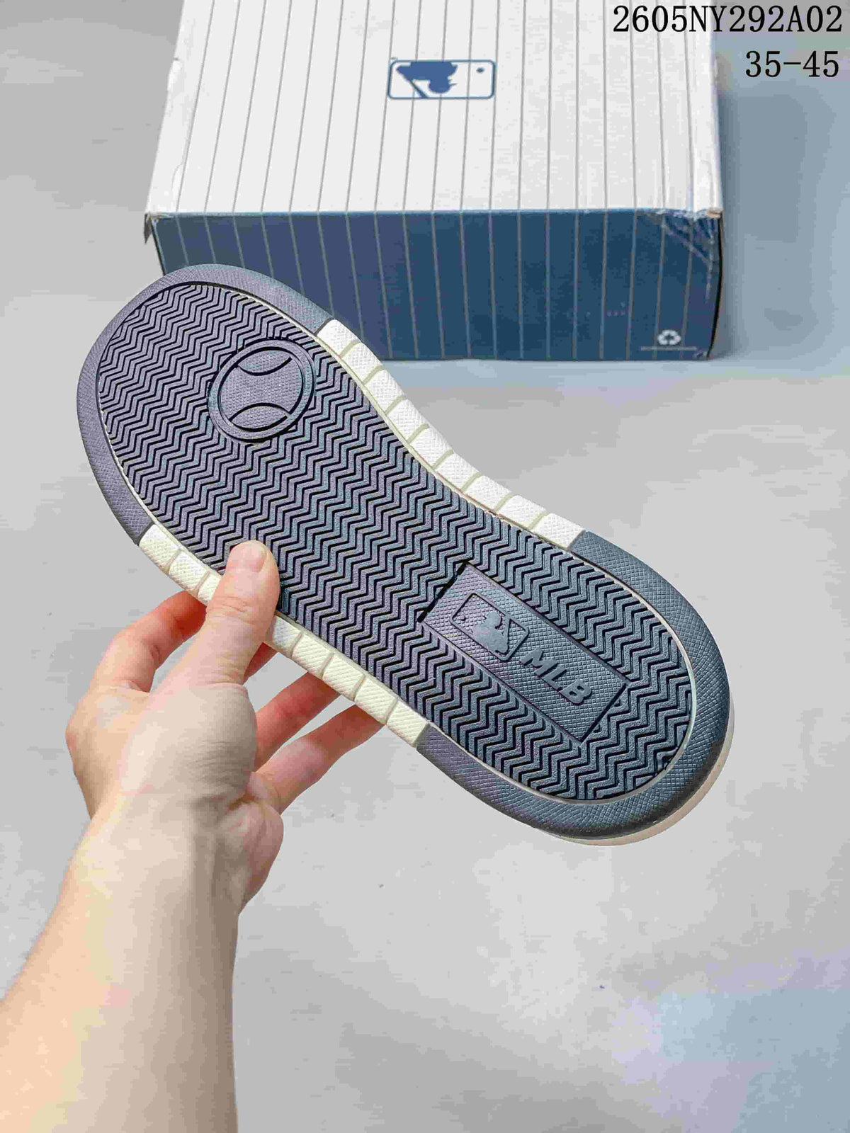 Close view of the sneaker outsole showing a repeating zigzag tread pattern and molded branding details.
