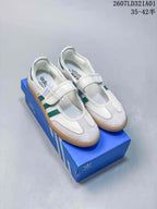 White Samba Jane sneakers with green stripes and gum-colored outsoles, shown on a blue shoebox.