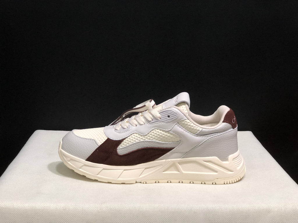 Side profile of one low-top sneaker showing the layered upper and geometric sole construction.