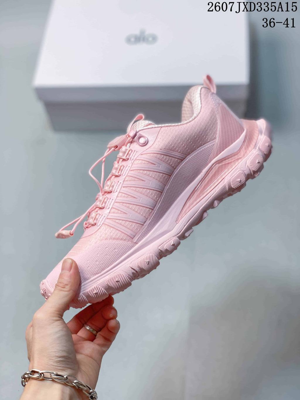 Side view of a pink Alo Yoga sneaker showing the layered panels, textured upper and lugged outsole.