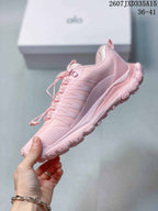 Side view of a pink Alo Yoga sneaker showing the layered panels, textured upper and lugged outsole.