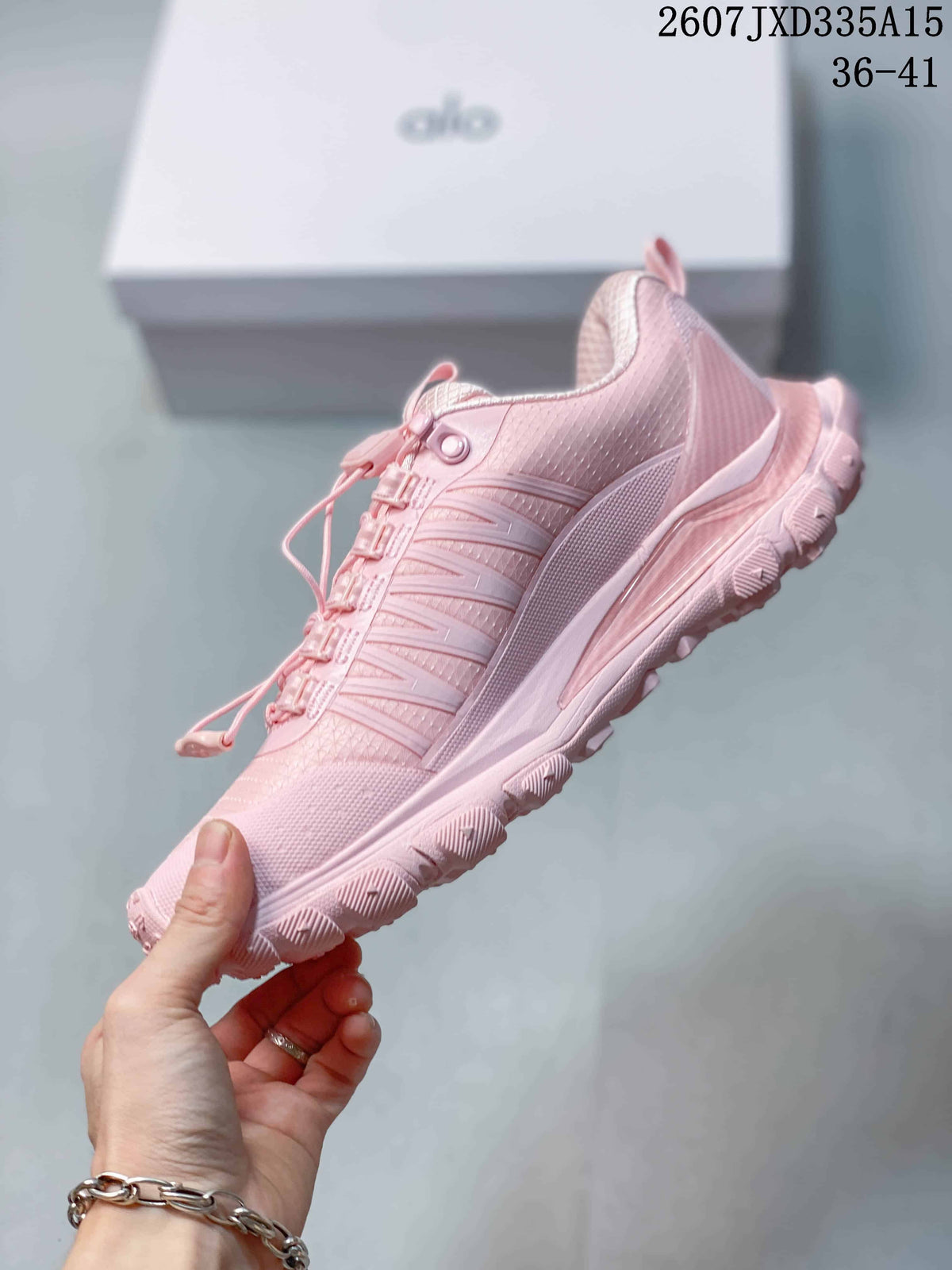 Side view of a pink Alo Yoga sneaker showing the layered panels, textured upper and lugged outsole.