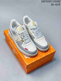 Off-white and pale grey low-top sneakers with patterned panels and a gold-tone lace charm, photographed on an orange shoe box.
