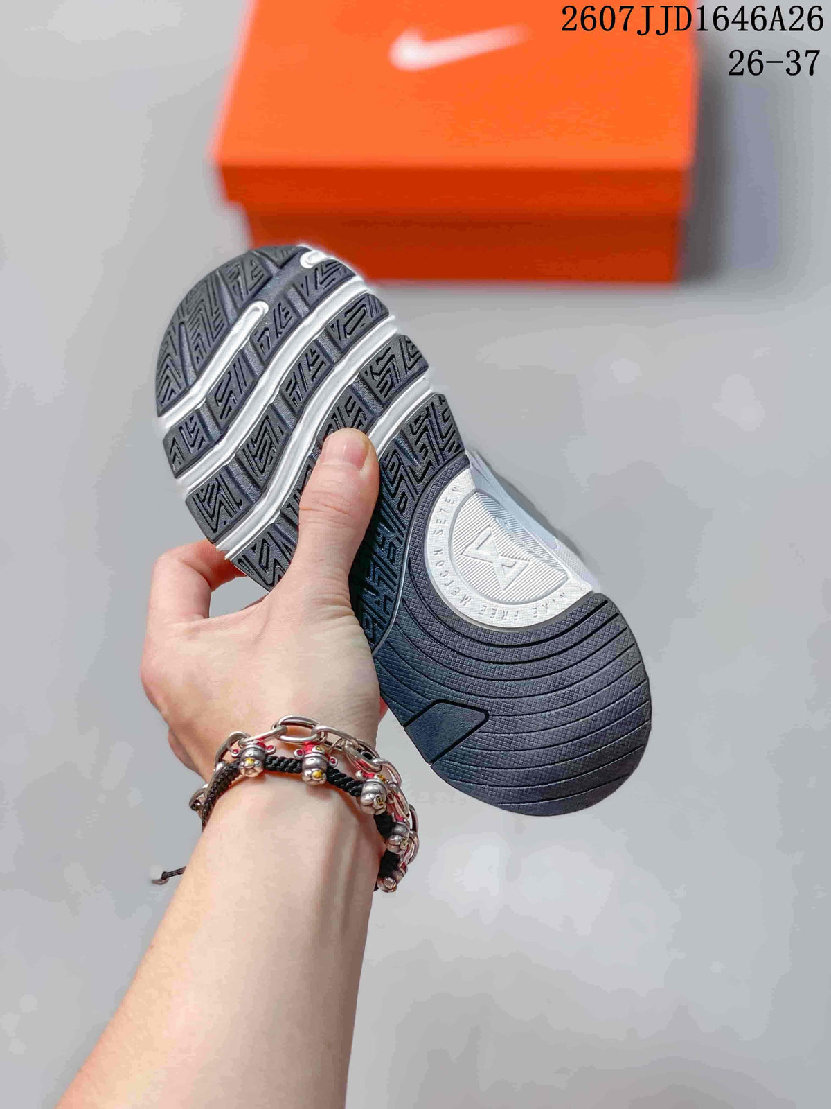 Underside view showing the patterned outsole of a gray and white Nike Free Metcon 7 children's sneaker.