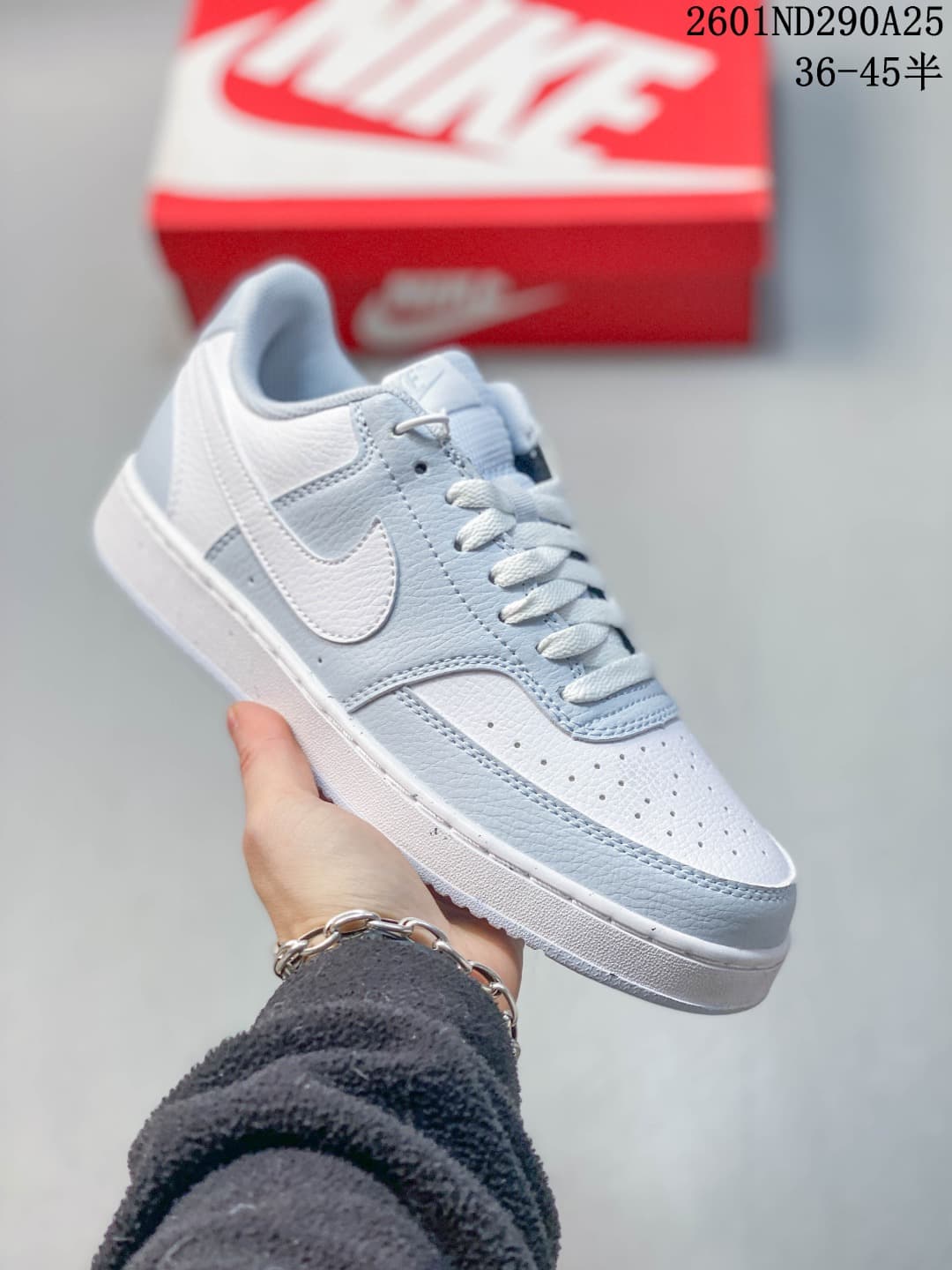 White Nike Court Vision Low sneaker with light blue overlays and a matching light blue Swoosh.