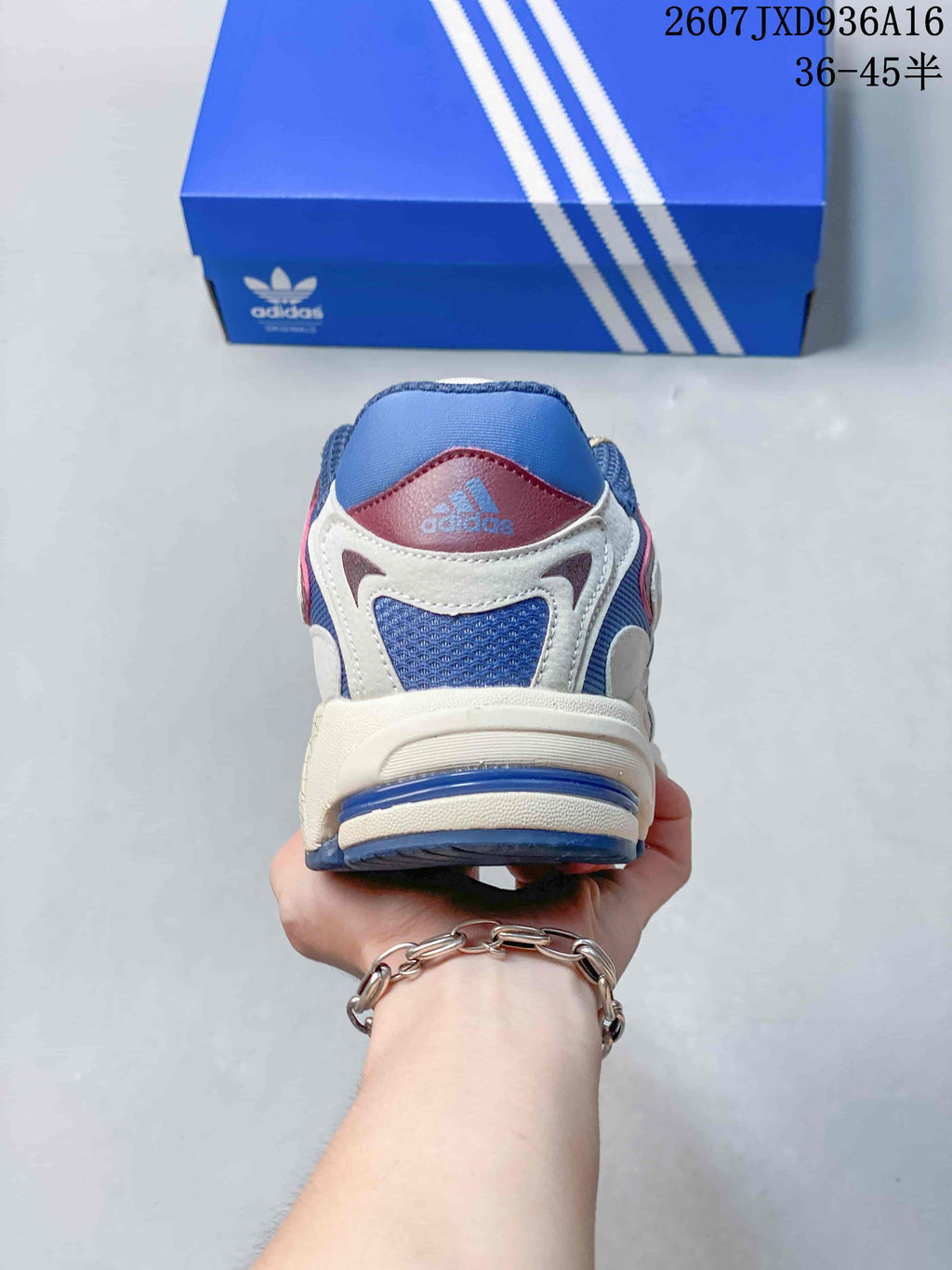 Rear view of the sneaker showing the padded blue collar, cream heel overlays and adidas branding.