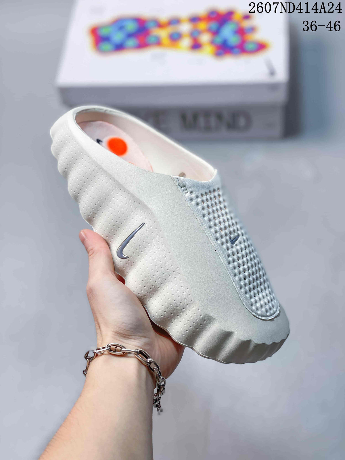 White Nike Mind 001 slip-on slide shown from the side, highlighting its perforated panels and scalloped outsole.