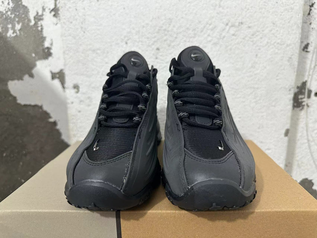 Front view of black Nike Air Max SNDR sneakers with laces and mesh-like toe panels.