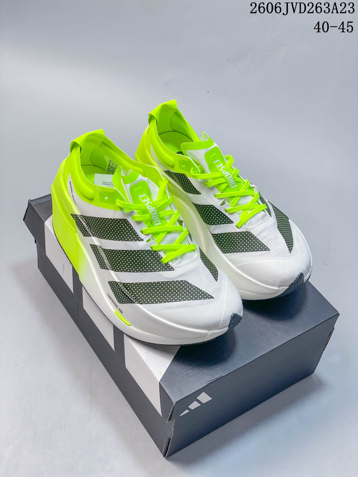 Pair of white Adidas Adizero Dropset Elite shoes with dark patterned stripes and neon-yellow accents, shown on a shoebox.