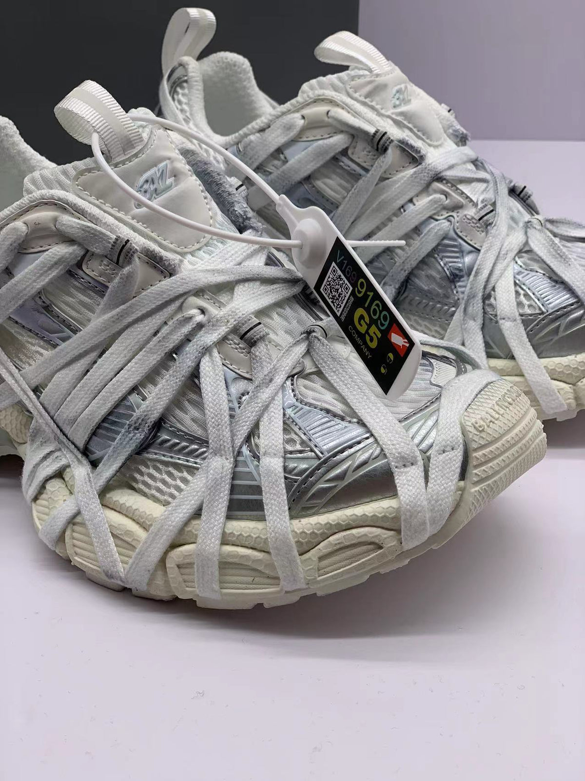 Close-up of the sneaker toe, laces, textured panels, and attached product tag.