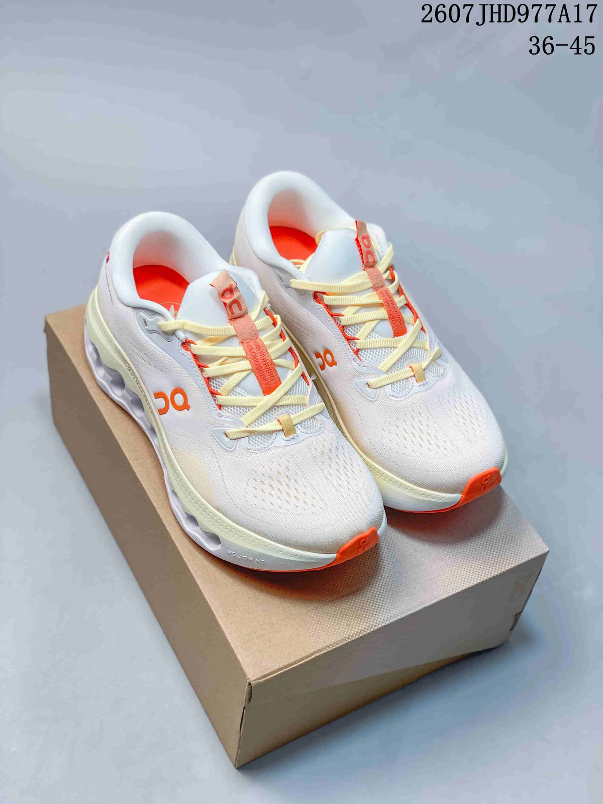 Pair of white On Cloudtilt sneakers with orange and cream accents displayed on a shoe box.
