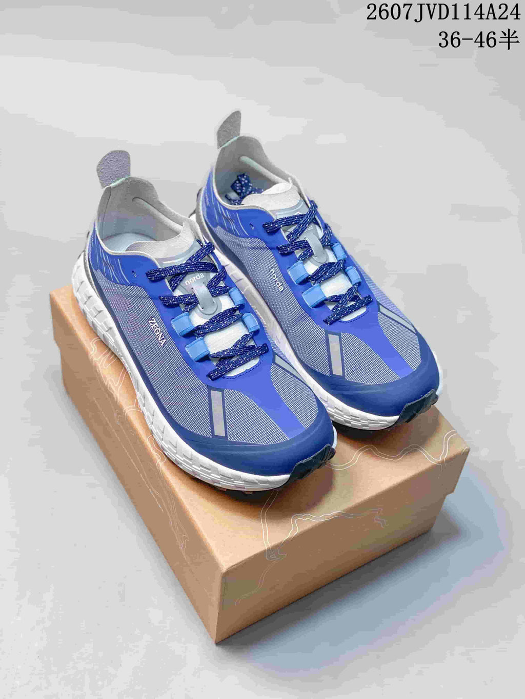 Blue and white NORDA sneakers shown from above on a shoebox, with product code 2607JVD114A24 and size range text visible.