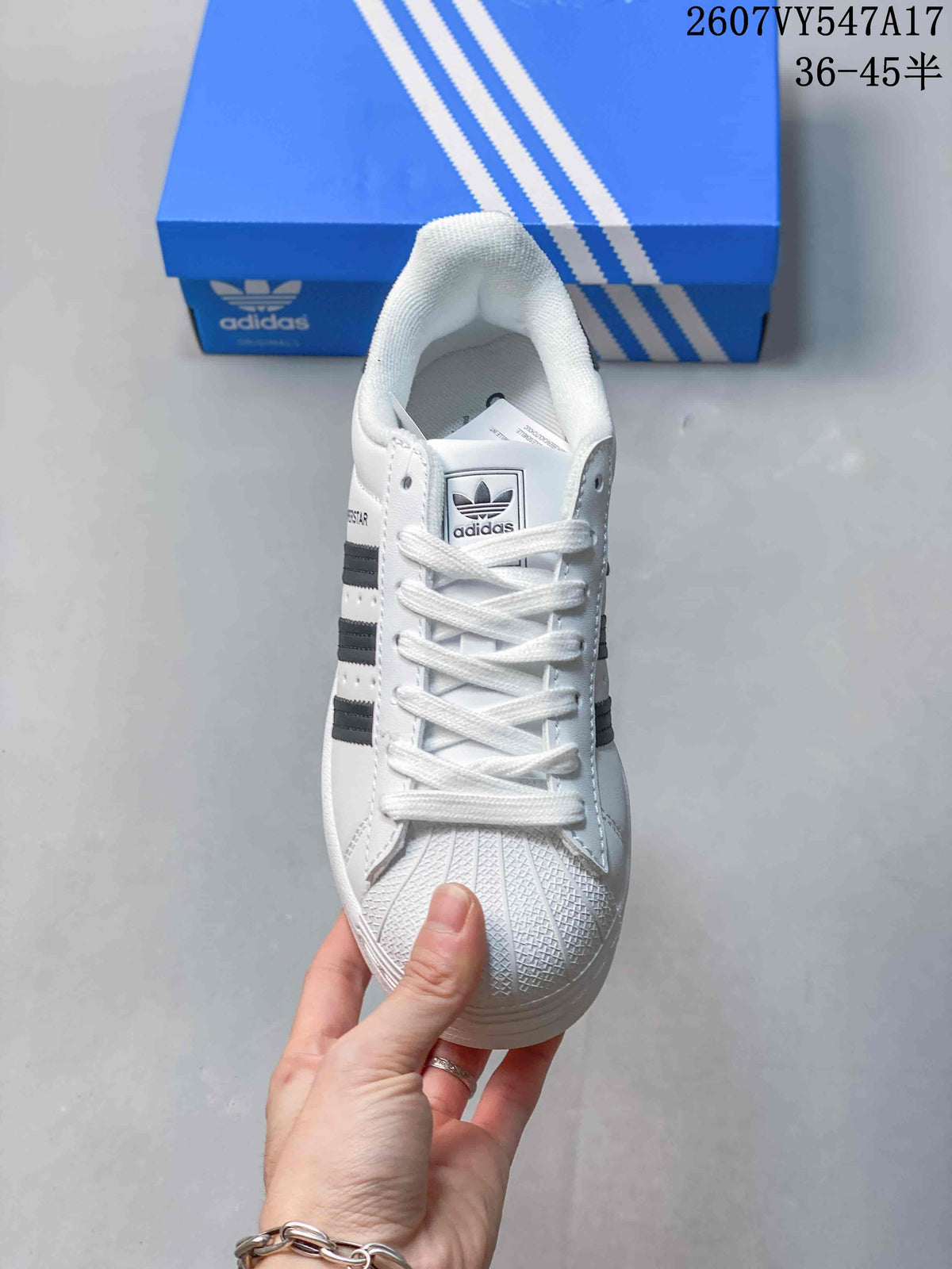 Top view of the white lace-up sneaker showing the tongue branding, shell-style toe texture, and black side stripes.