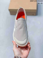 Top view showing the light gray textile-look upper, wide tongue panel, and orange interior lining.