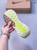 Close view of the patterned outsole showing light gray, burgundy, and neon yellow sections with raised traction lugs.