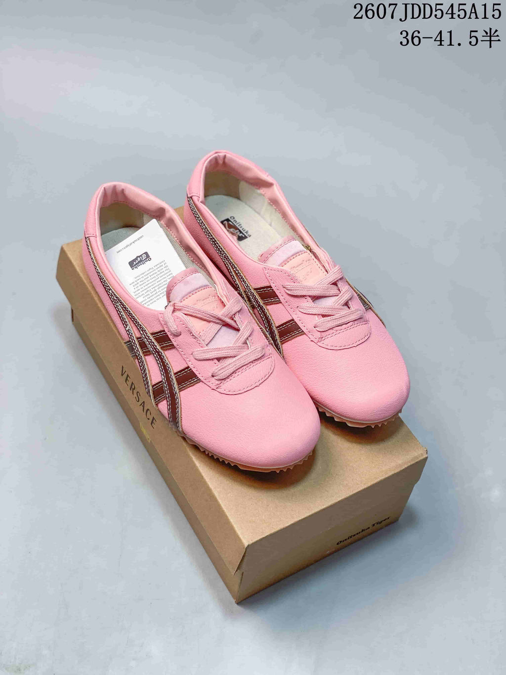 Pair of pink Versace x Onitsuka Tiger low-top sneakers displayed on a branded shoebox.