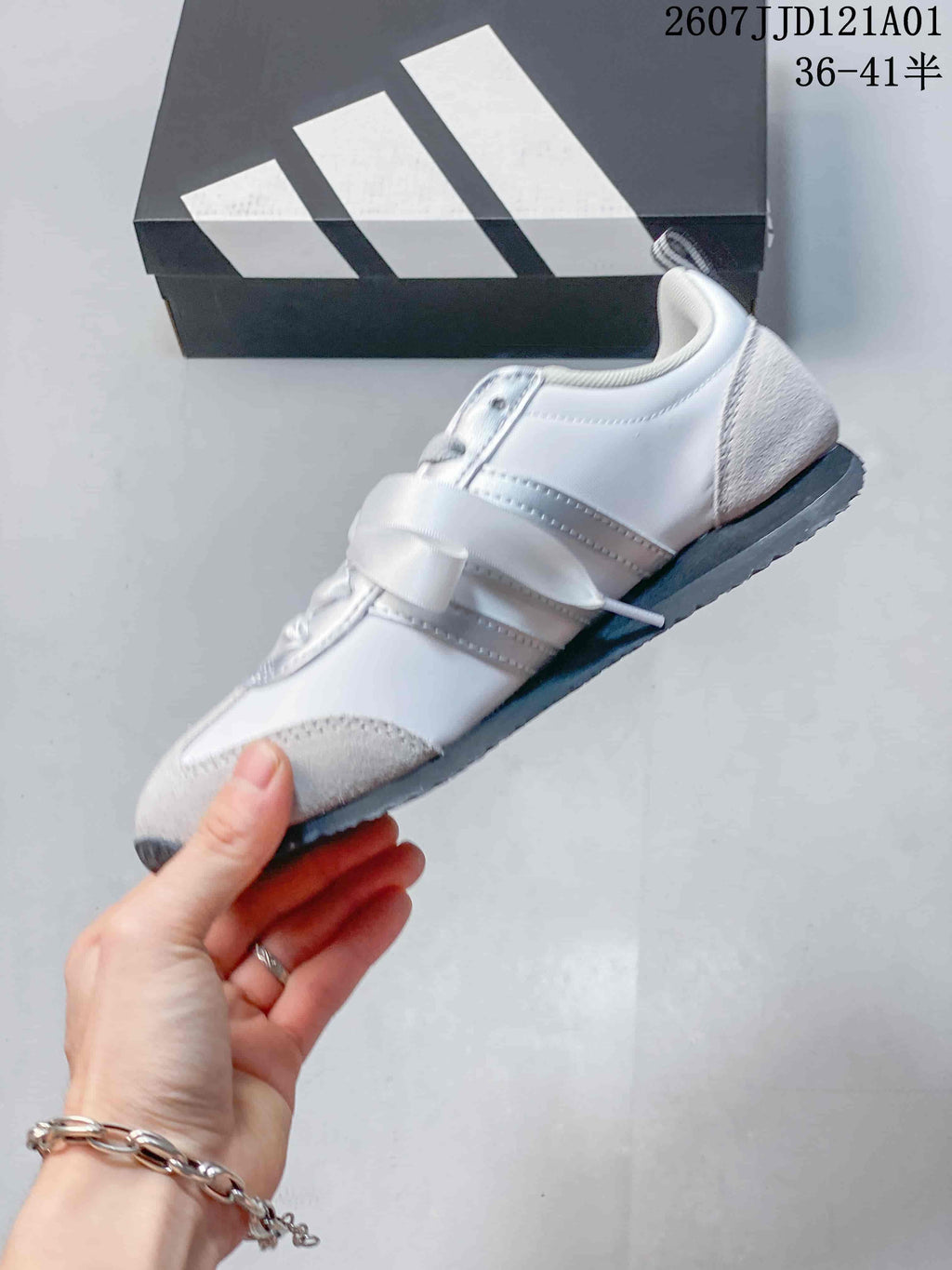 Side view of a white and gray low-profile sneaker with ribbon laces
