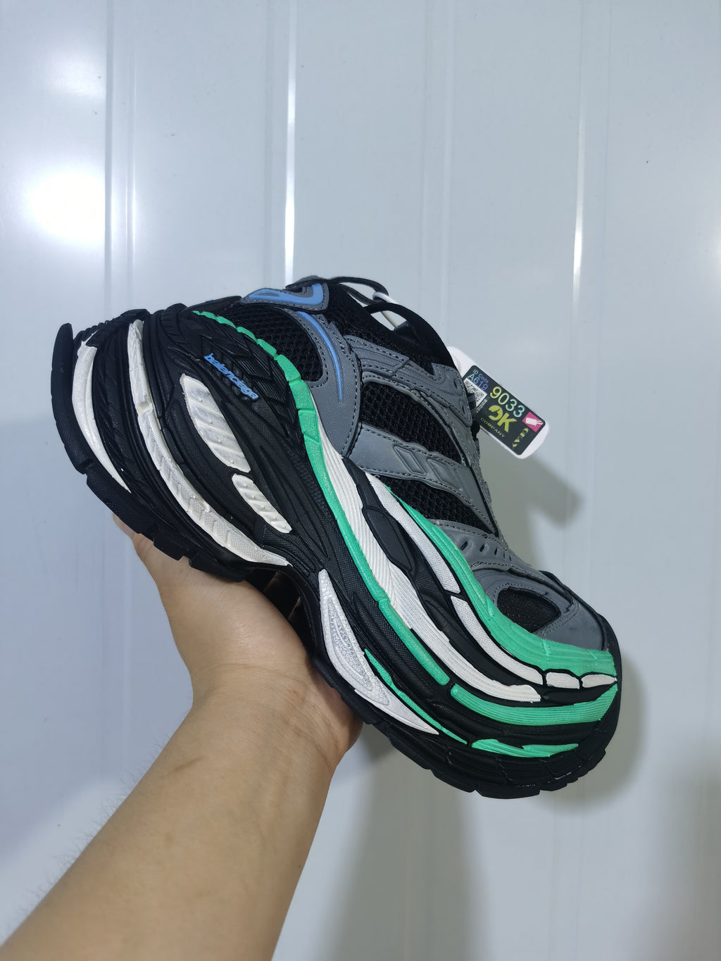 Three-quarter view of the sneaker highlighting the black, white and green sole construction and mesh upper.