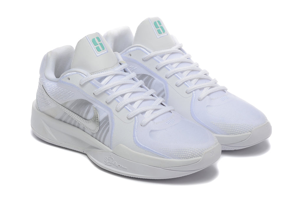 Angled view of a pair of white basketball shoes with silver-tone Swooshes and teal tongue details.