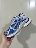 Close-up side view of a white and blue Balenciaga Runner sneaker showing mesh panels, layered overlays, and a clear heel section.