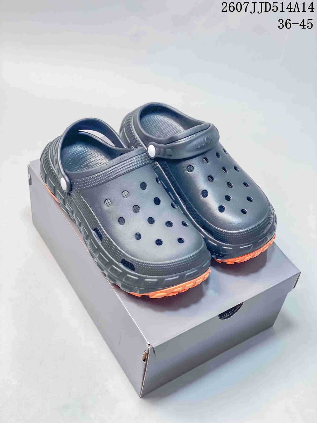 Pair of black perforated clog sandals with orange tread, shown on a shoe box; model text 2607JJD514A14 and size range 36–45 are visible.