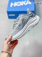 Side profile of the gray running sneaker showing the mesh-style upper, lace system, raised heel, and layered white sole.