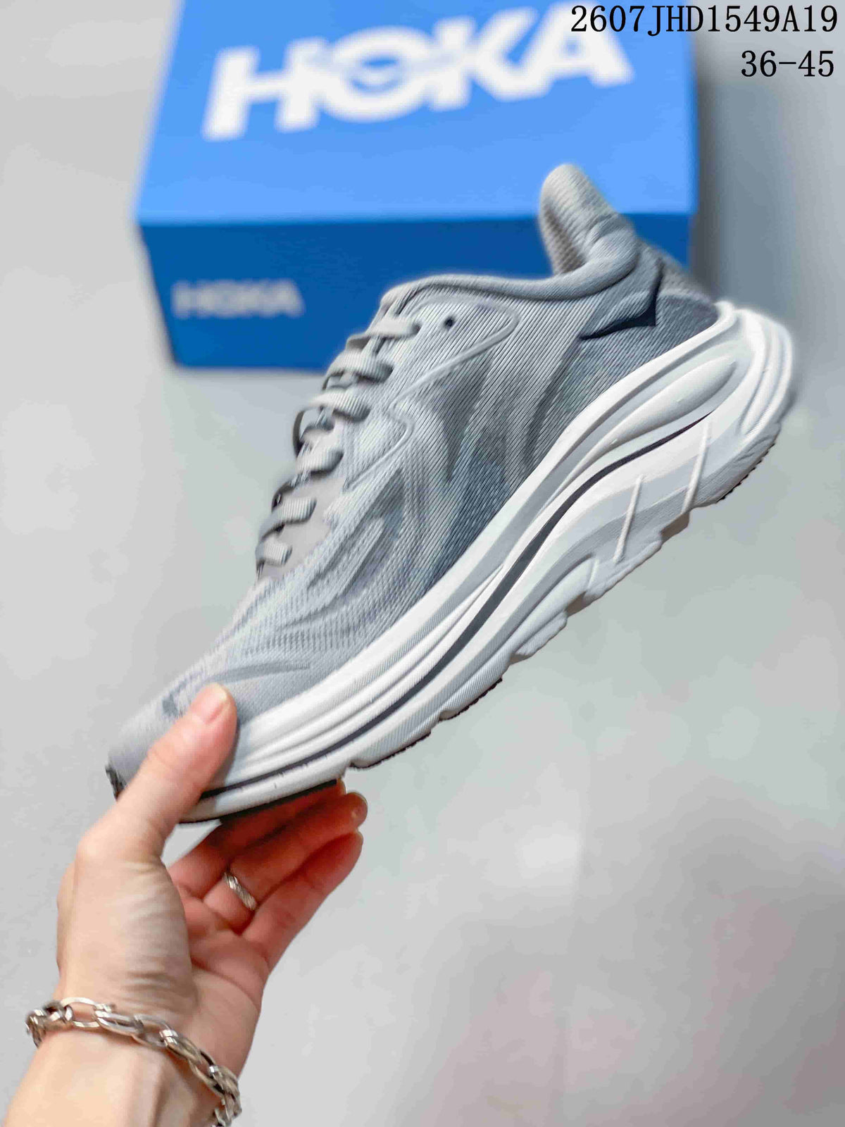 Side profile of the gray running sneaker showing the mesh-style upper, lace system, raised heel, and layered white sole.