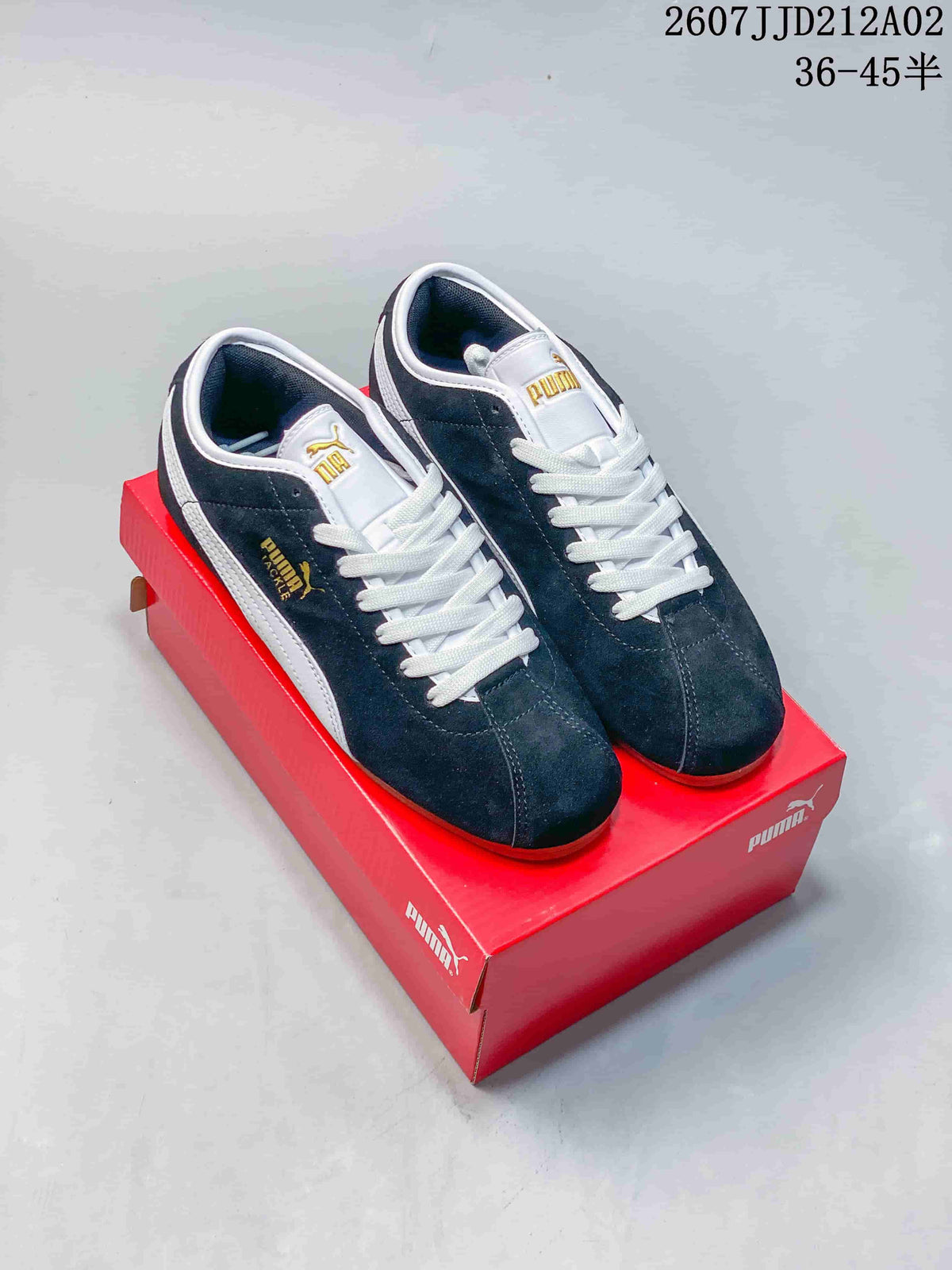 Pair of navy PUMA Tackle low-top sneakers with white laces and detailing on a red shoebox