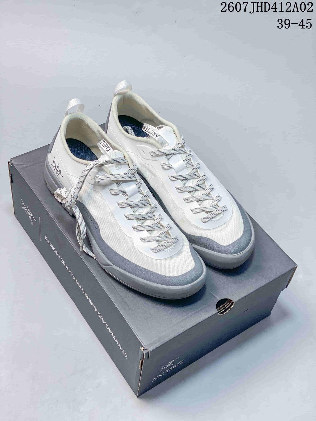 Pair of white and gray Arc'teryx Konseal LT W shoes displayed on a shoe box