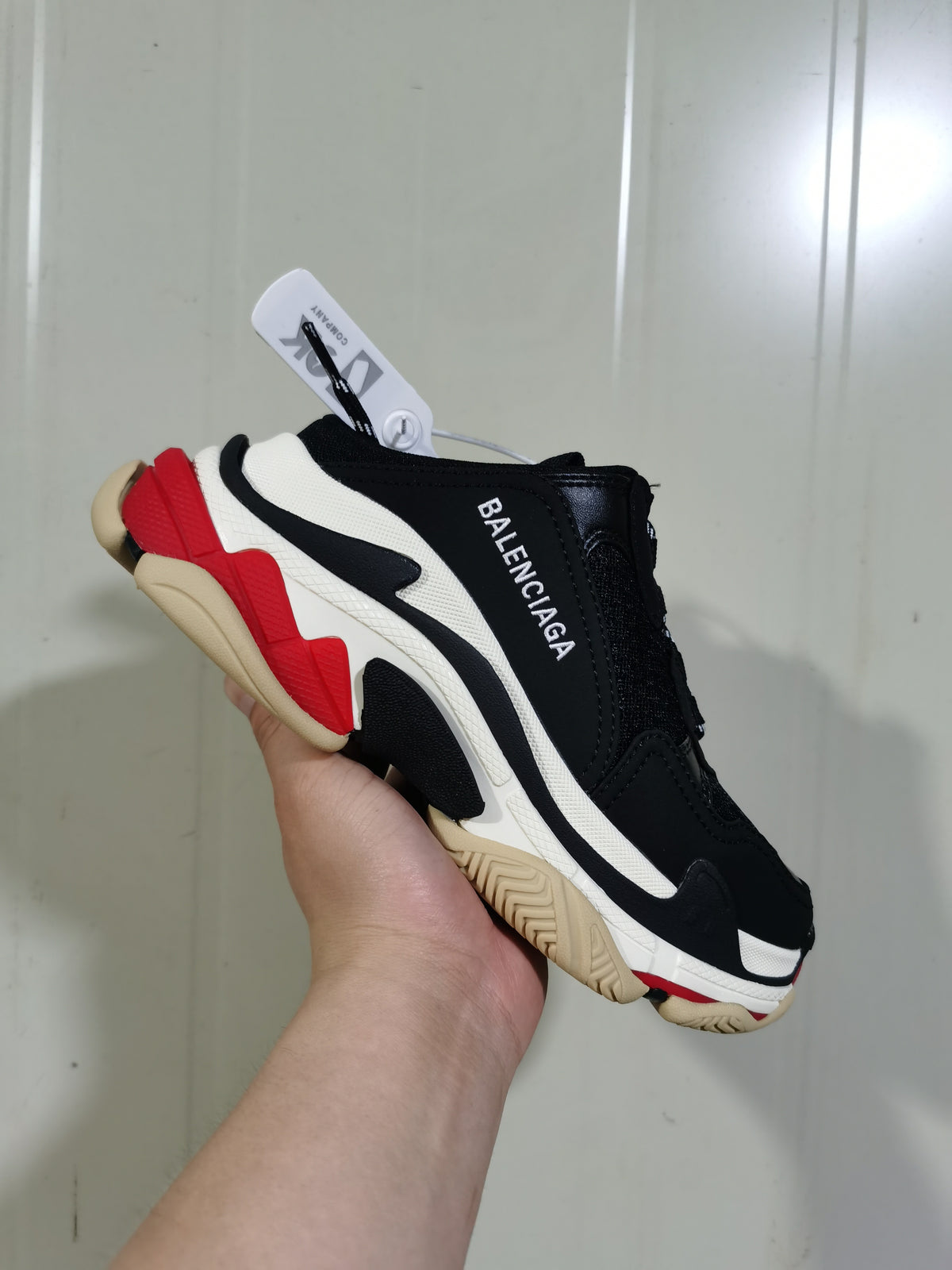 Angled view showing the black upper, white layered side panel, red heel detail, and Balenciaga branding.