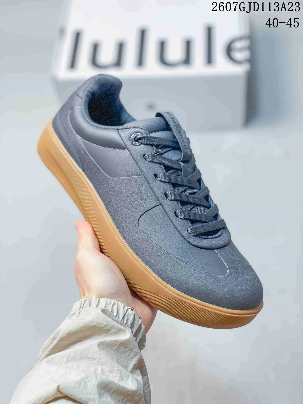Side view of a dark gray lululemon Cityverse sneaker with tonal panels and a gum-colored rubber outsole; image text shows style code 2607GJD113A23 and size range 40–45.