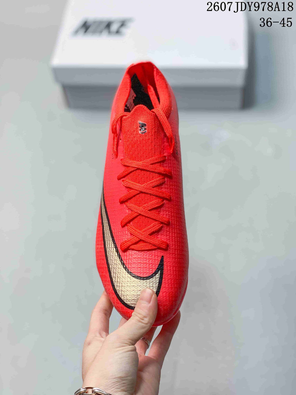 Top view of the red soccer cleat showing the laces, textured upper, and large black-and-gold swoosh.