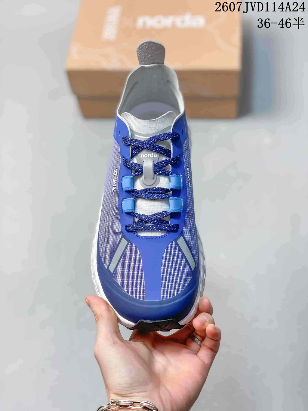 Top view of one blue and white NORDA sneaker showing the laces, tongue, toe panels, and reflective-looking details.