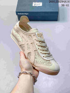 Close-up of a beige Onitsuka Tiger sneaker with patterned textile panels, lace-up closure, stitched side detailing, and a flat outsole.