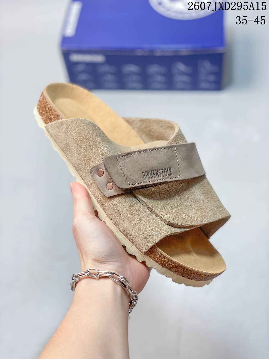 Angled close view of the taupe sandal showing the buckle strap, suede upper, open-back profile and cork-look midsole.