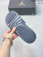 Close view of the patterned outsole on a white and navy slide, showing repeating traction shapes and segmented grooves.