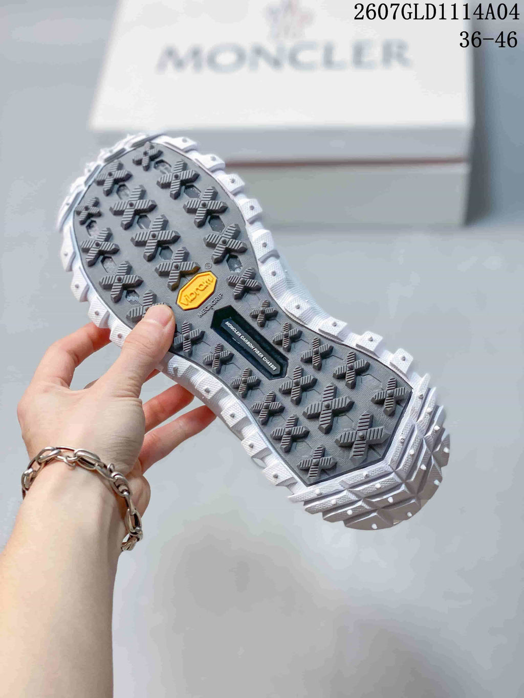 Close view of the sneaker outsole showing a dark patterned tread, raised lugs and branded inserts.