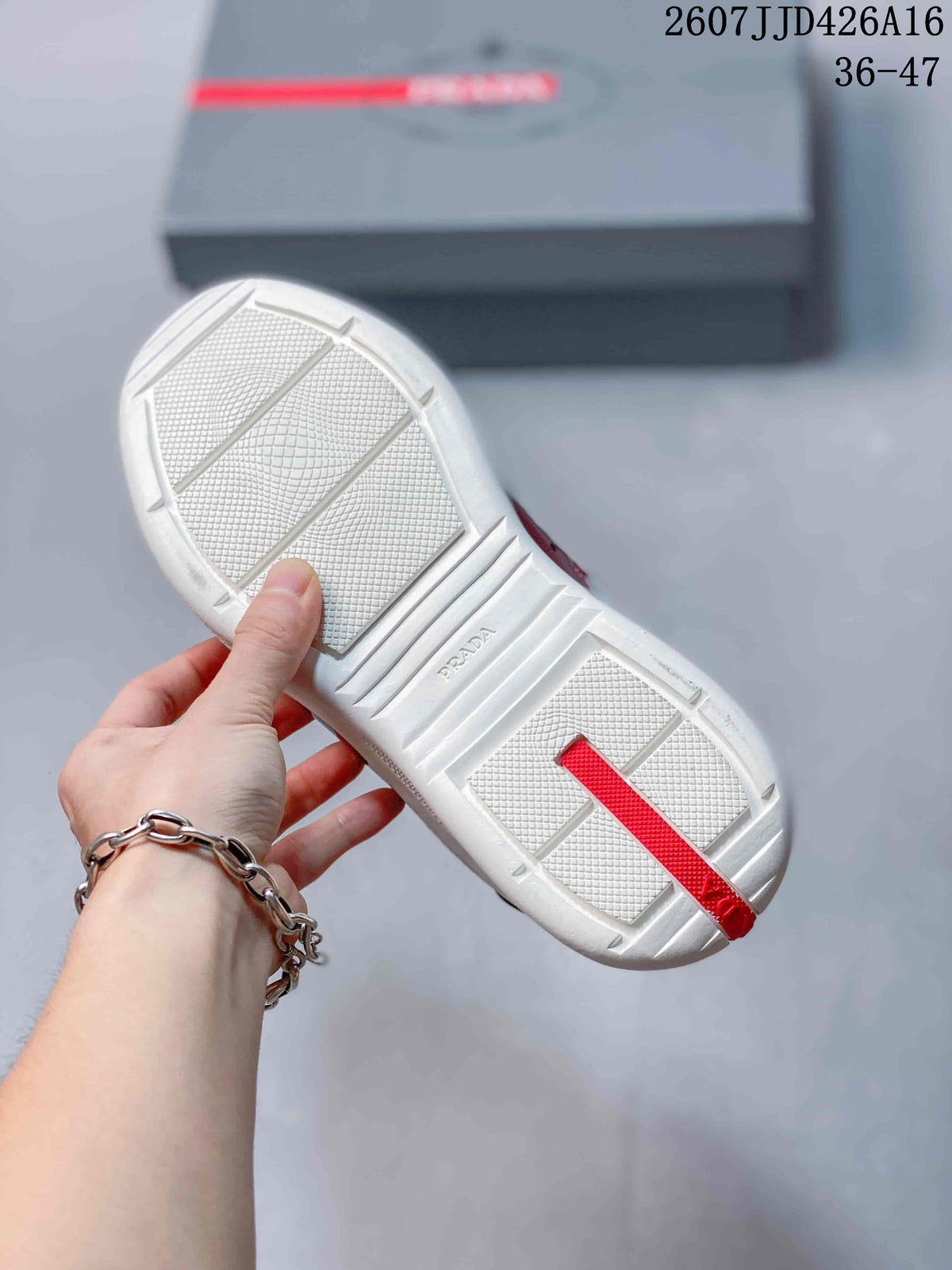 Underside view of a white sneaker outsole with textured traction areas, raised grooves, and Prada lettering.