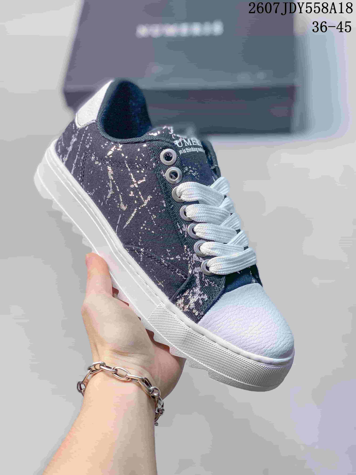 Dark NUMERIS low-top sneaker with a light splatter-style print, white laces and a white toe cap; image shows size range 36-45.