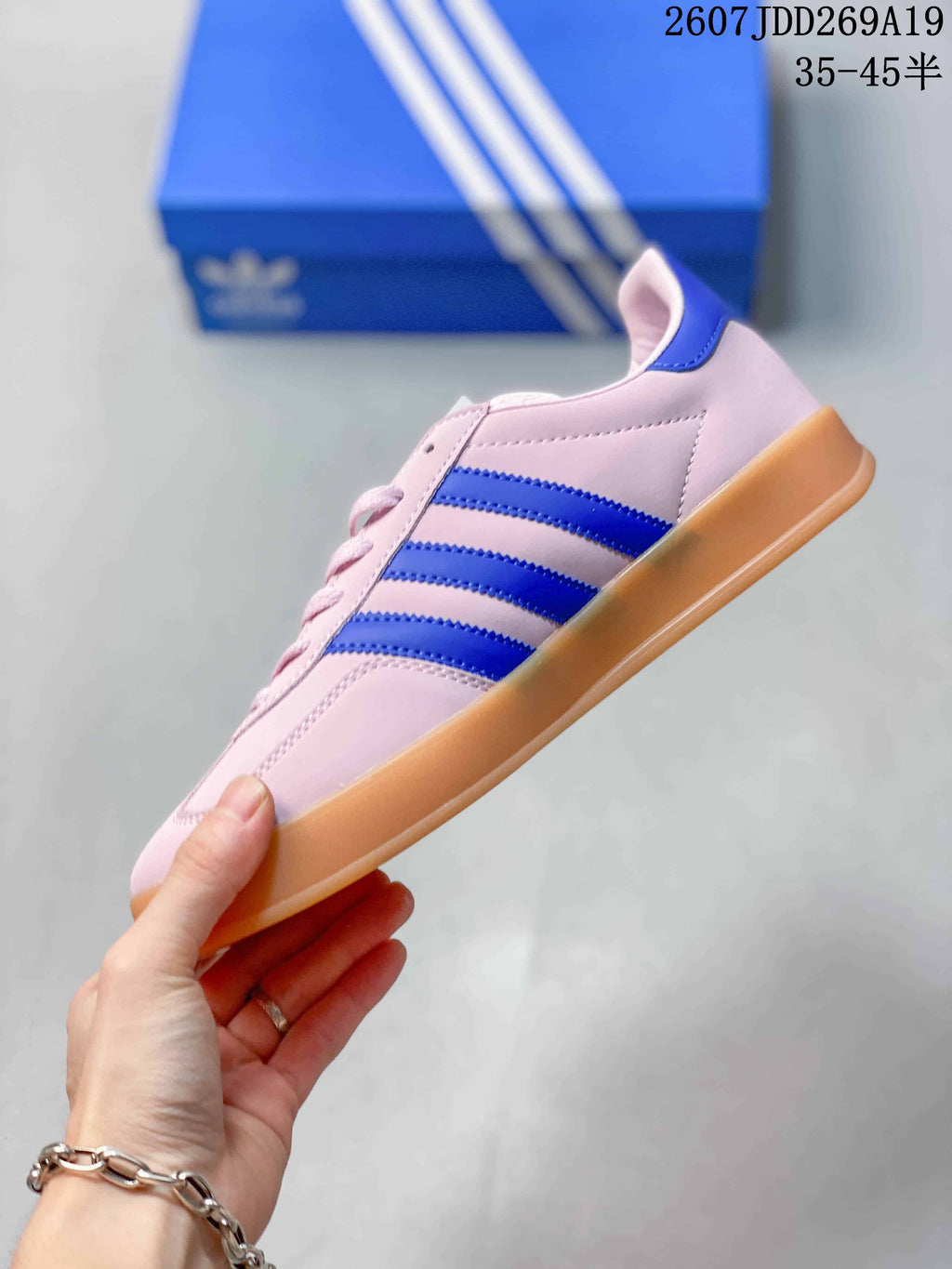 Side view highlighting the three blue stripes on the pink upper and gum-colored sole.
