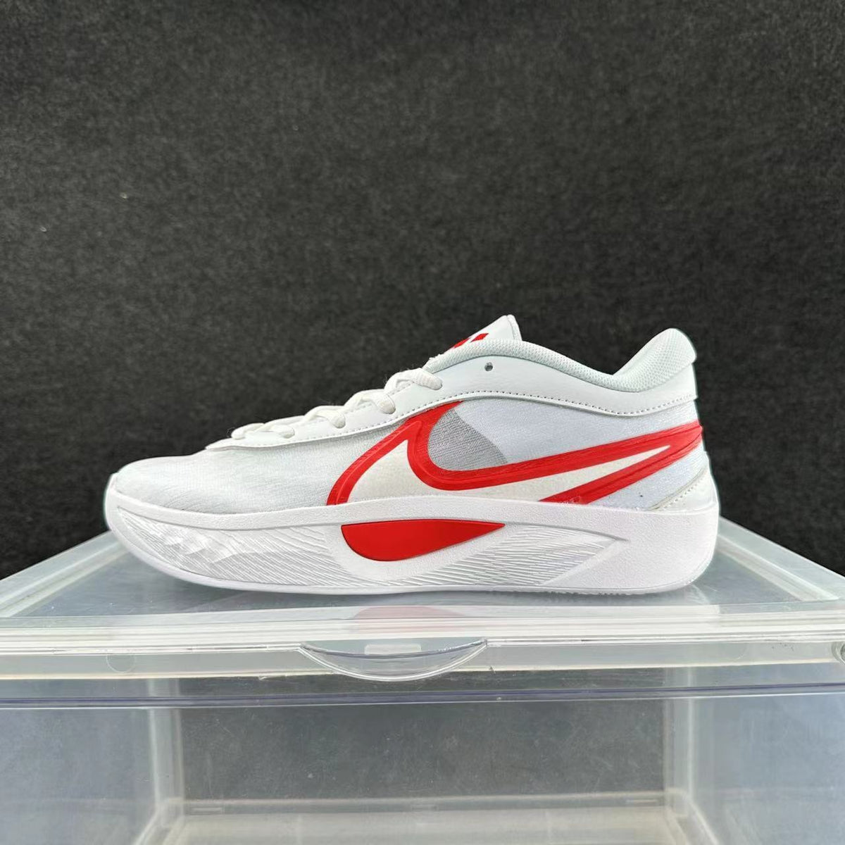 White low-top sneaker with red side detailing and a raised white sole, shown from the side.