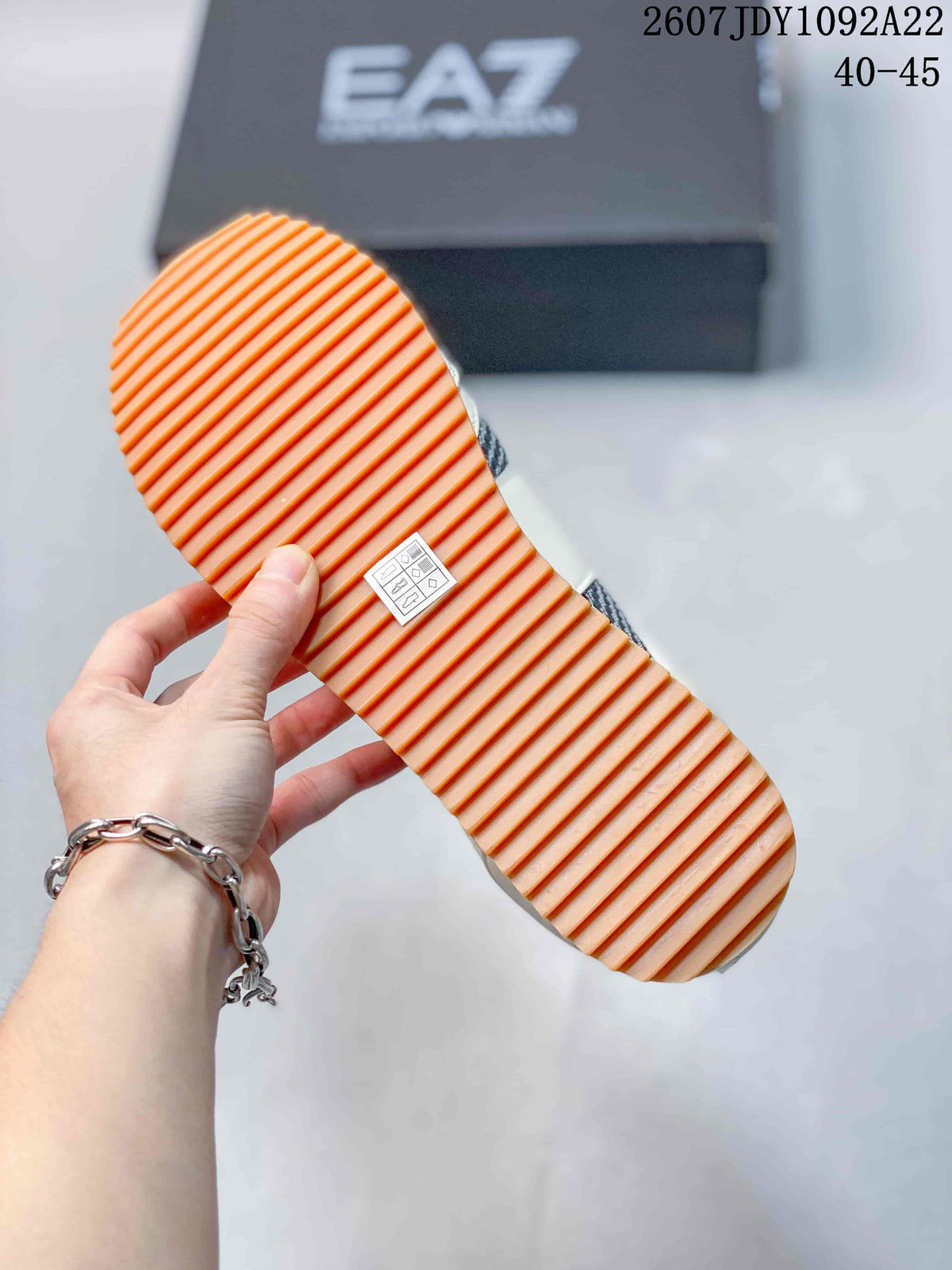 Close view of the sneaker outsole showing a raised orange-toned ribbed tread pattern.