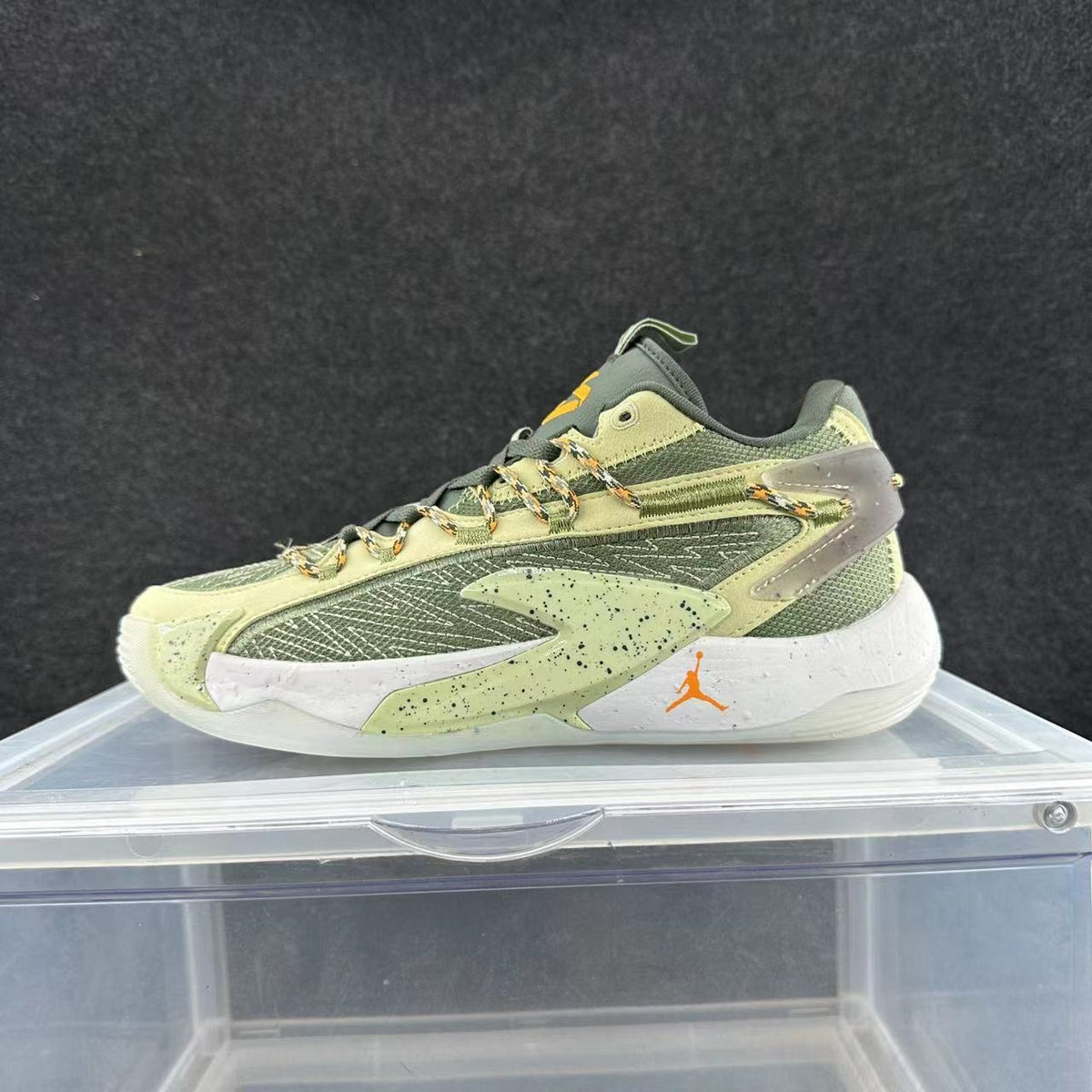 Side view of green, pale yellow and orange Jordan basketball sneakers with patterned laces and a speckled white midsole.