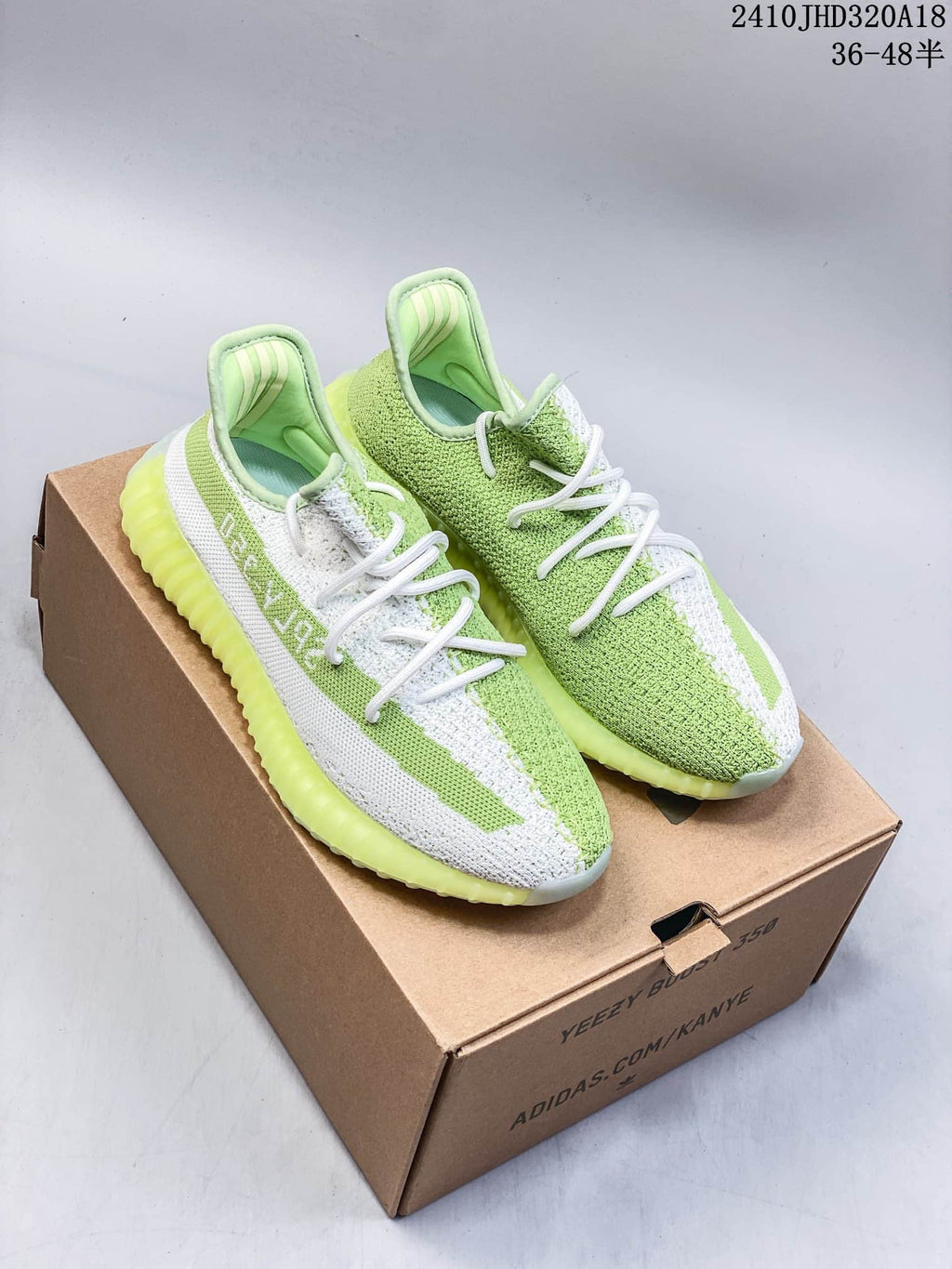 Pair of light green and white Adidas Yeezy Boost 350 sneakers displayed on a cardboard shoe box.