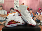 Two white Jordan high-top sneakers with red and orange accents shown at an angle.