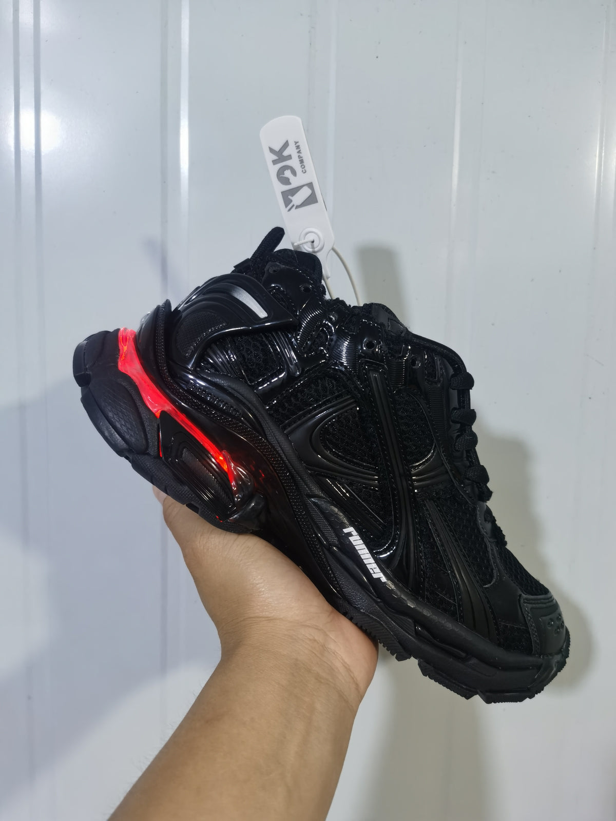 Black Puma Runner LED sneaker shown from a side and top angle, with layered panels, mesh sections, and a red illuminated heel accent.