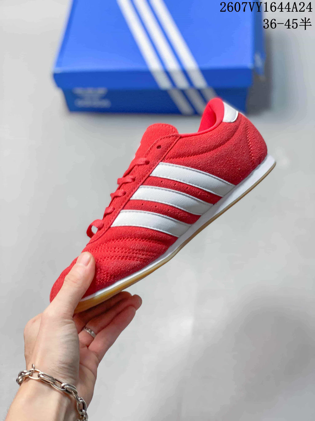 Side profile of the red adidas low-top sneaker with white three-stripe detailing and a gum-colored outsole.