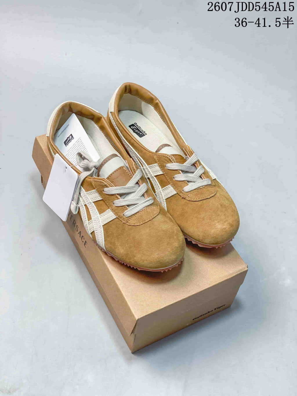 Pair of tan and cream Versace x Onitsuka Tiger sneakers displayed on a branded shoe box, with style code and size range text visible above.