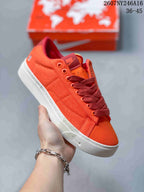 Angled side view of the orange Nike sneaker showing the low-top silhouette, stitched upper panels, and white outsole.
